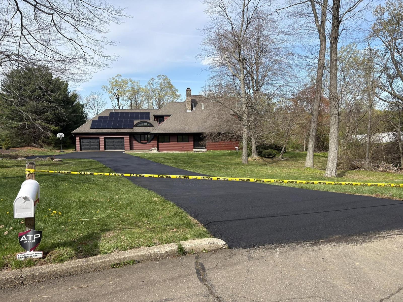 Long fresh asphalt driveway through a wooded lot
