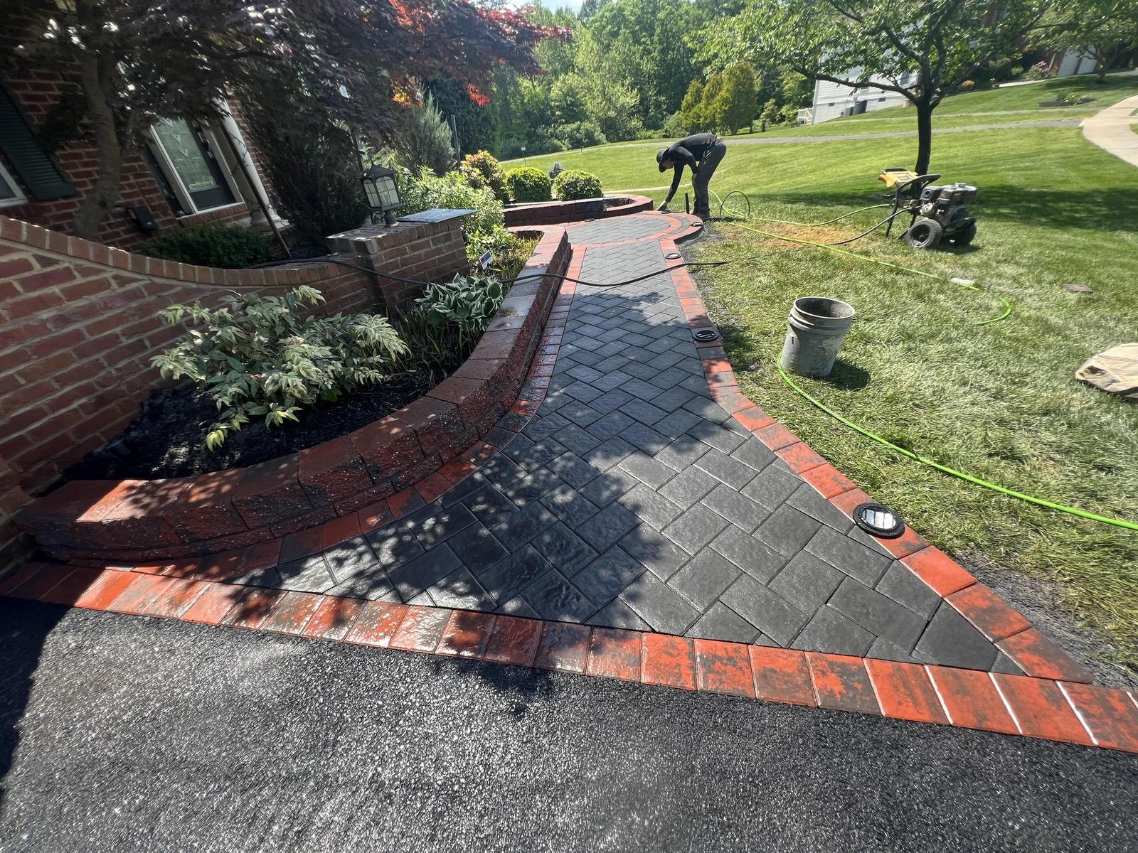 Brick retaining wall and paver walkway wrapping a landscaped front yard